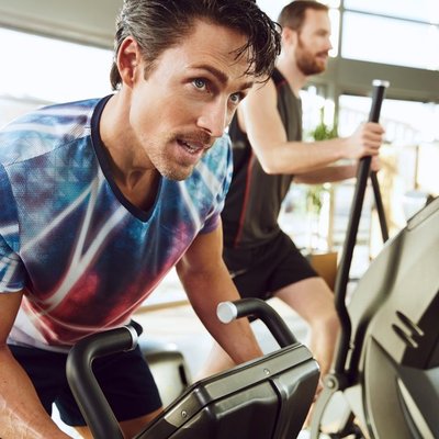 Mann trainiert im Fitnessstudio auf dem Ergometer